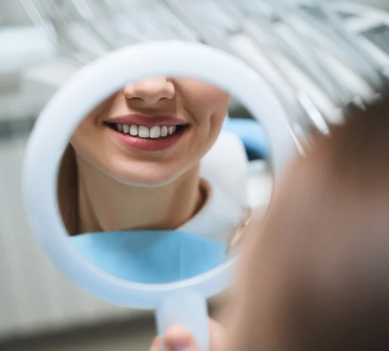 Woman checking her whitened teeth in a dental mirror