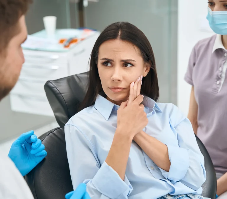 Patient holding her cheek during an emergency dental visit in Richardson, TX